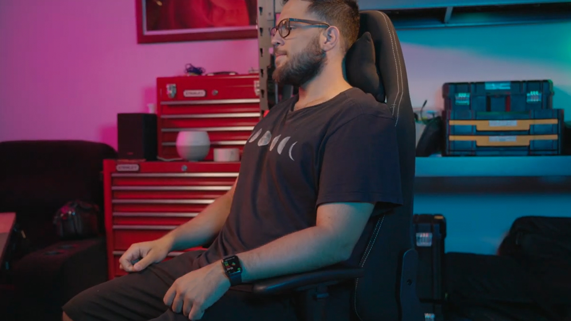 imagem de homem branco com uma camiseta preta sentado em uma cadeira de escritório