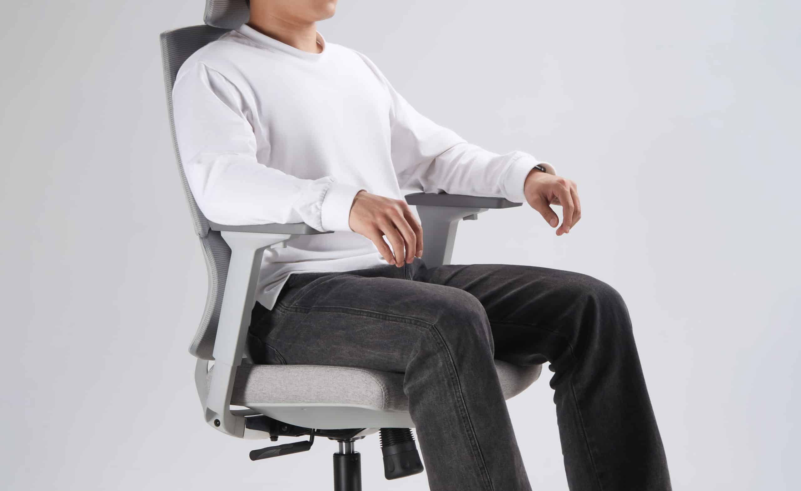 modelo sentado em uma cadeira de escritório slikdesk ergos cinza claro em um fundo branco