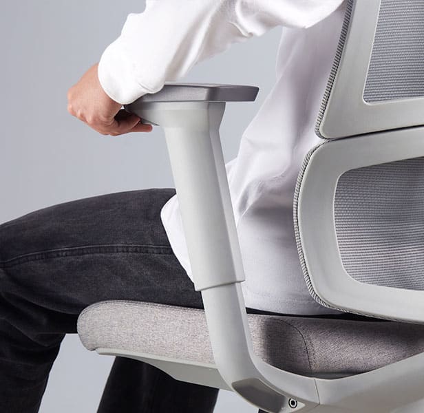 detalhe do apoio de braço 3D da cadeira ergonomica slikdesk ergo, modelo com camiseta branca e caixa jeasn preta sentado na cadeira cinza claro enquanto ajusta o apoio de braço